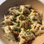 Blanket dumplings topped with chives and chilli oil.