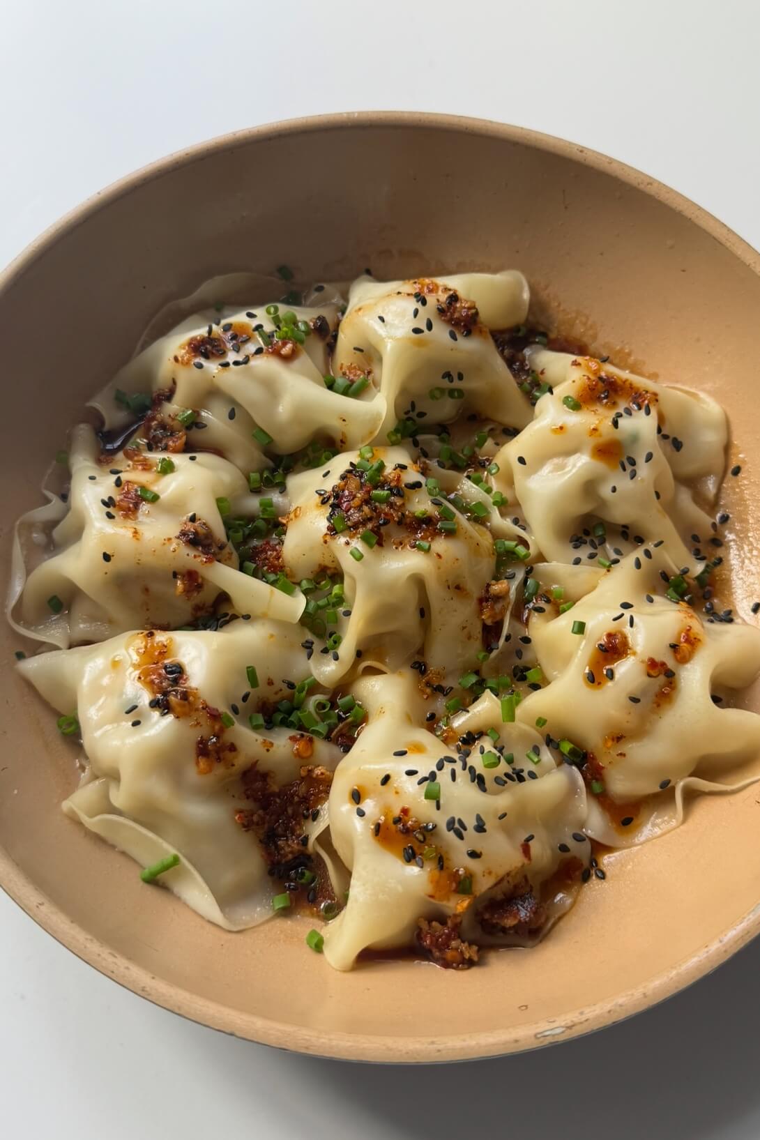 Blanket dumplings topped with chives and chilli oil.
