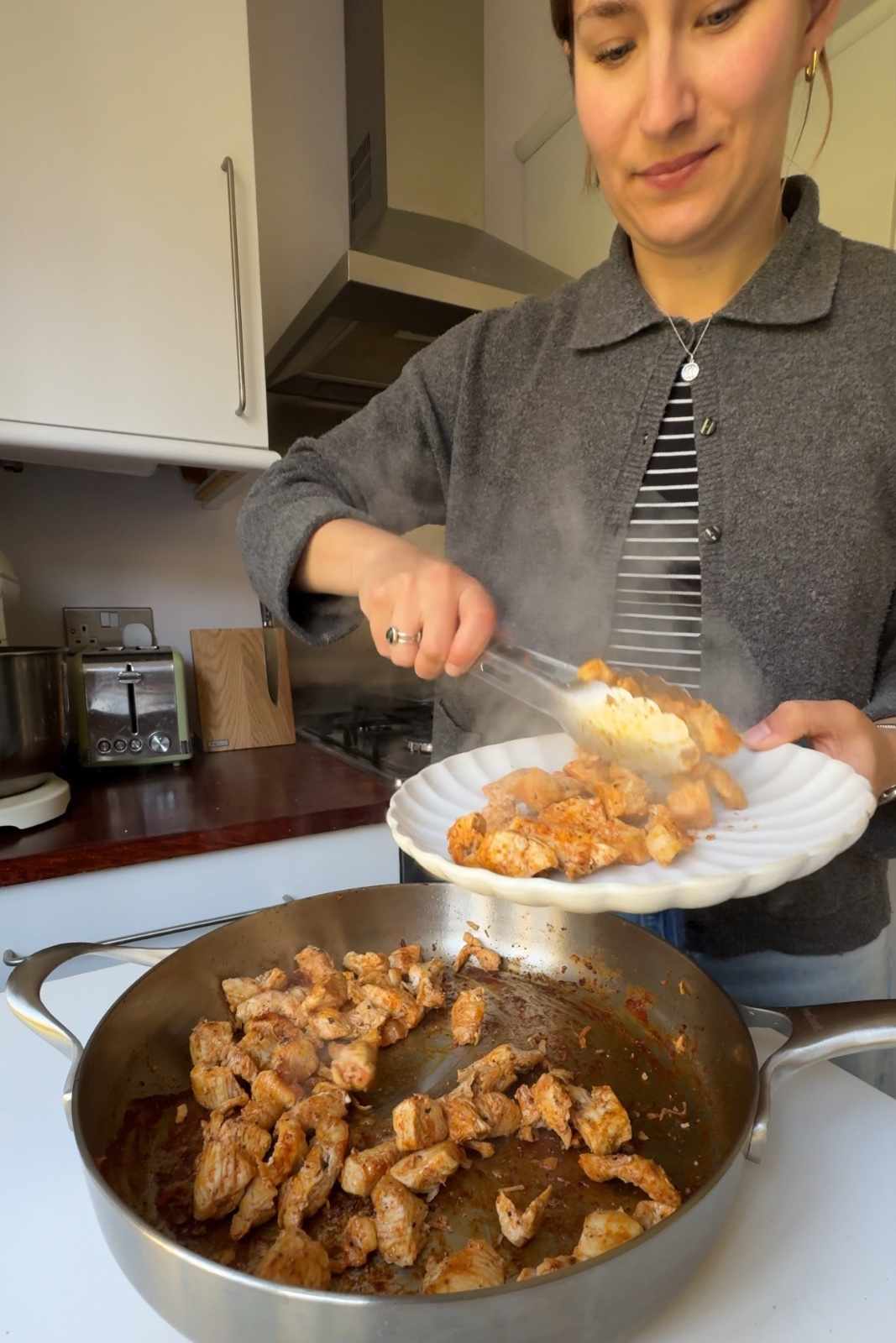 Emily Roz removing cooked chicken from pan.