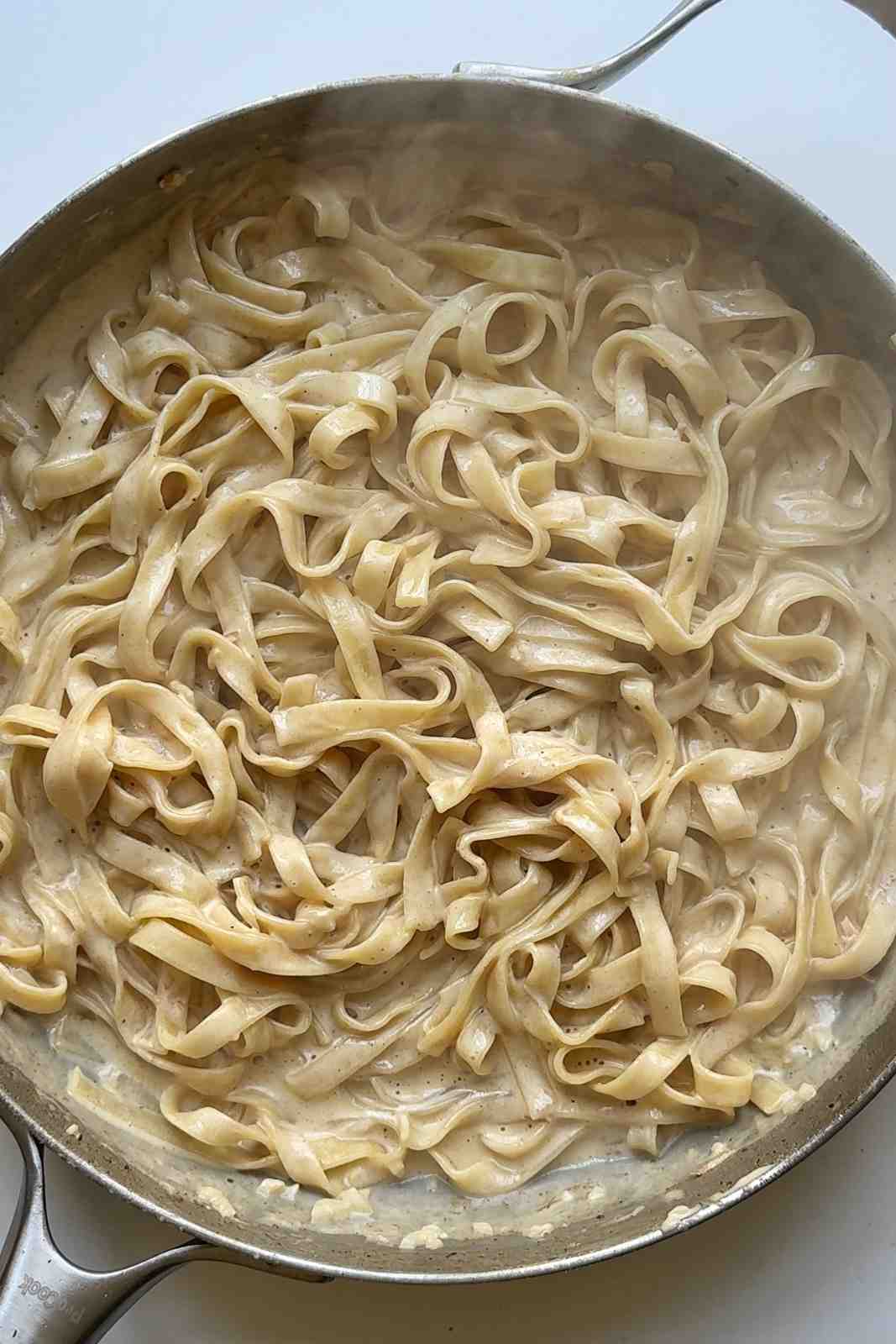 Cooked tagliatelle in a stainless steel pan.