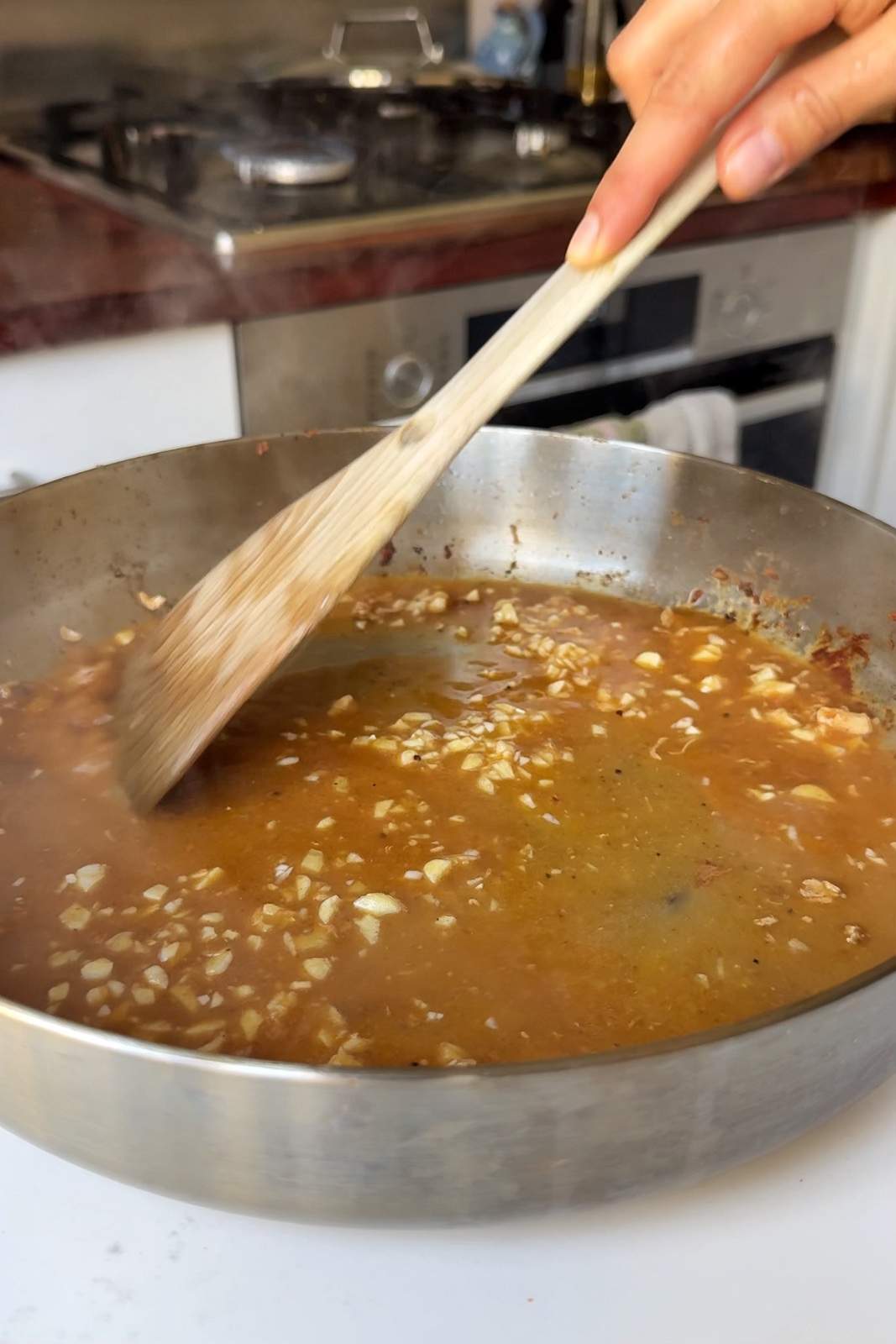 Stirring garlic in a pan with stock.