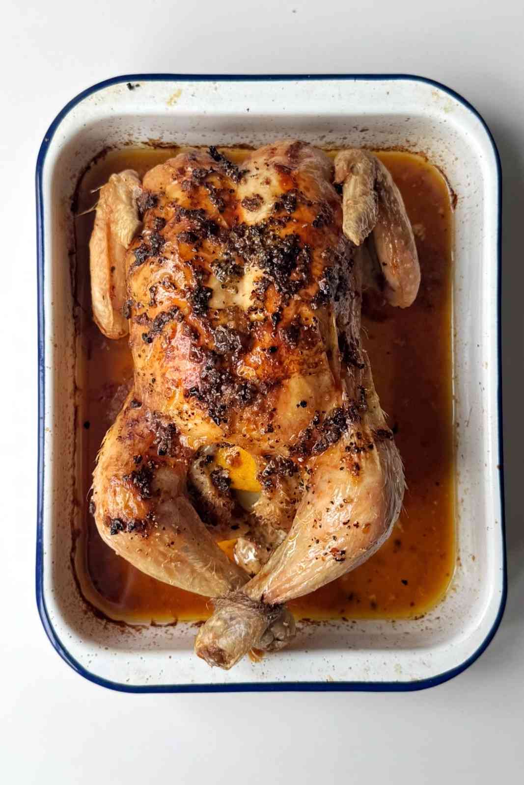 Roasted chicken in convection oven with brown skin in a baking tray.