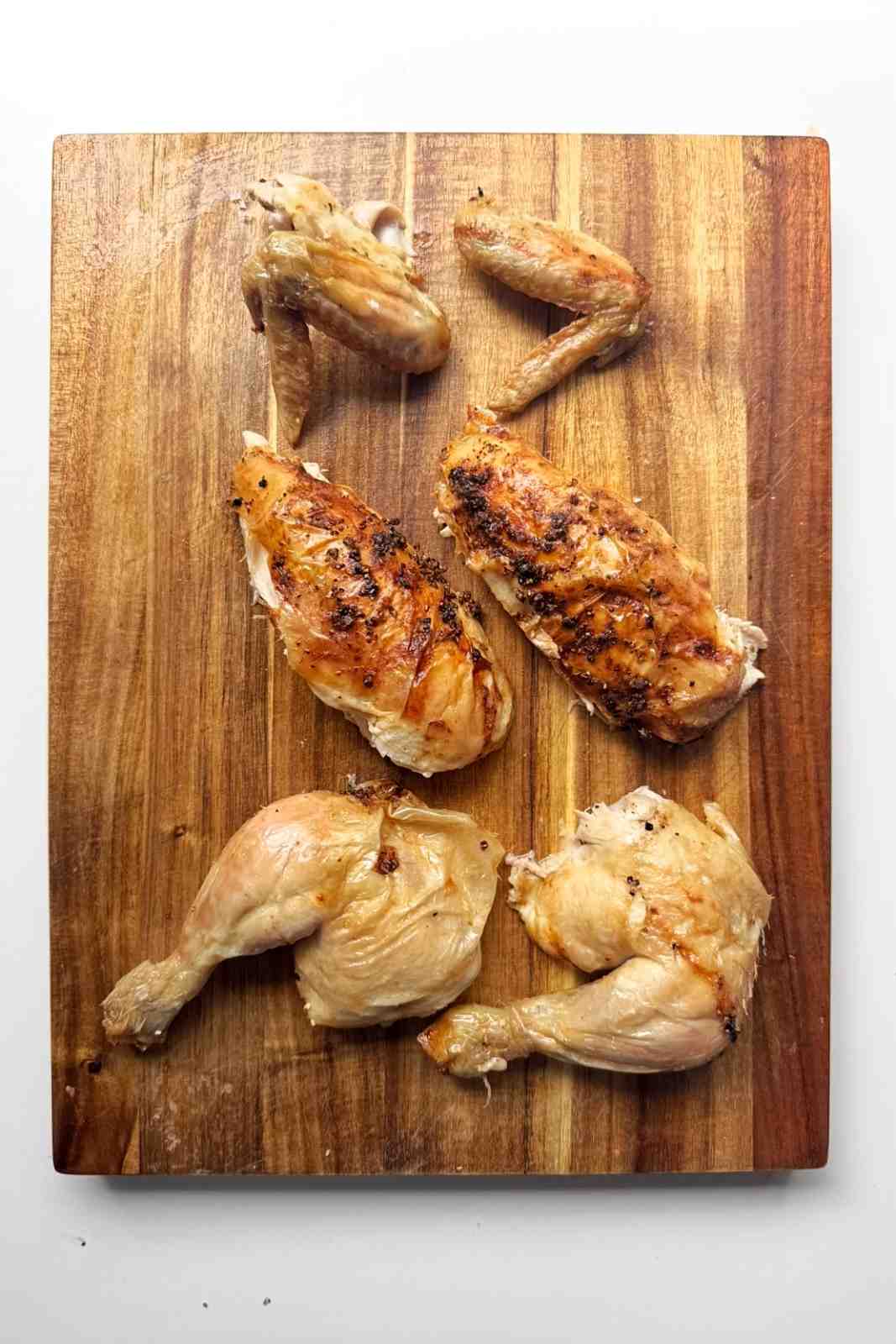 A whole roast chicken carved into the wings, the chicken breast, and the chicken legs.