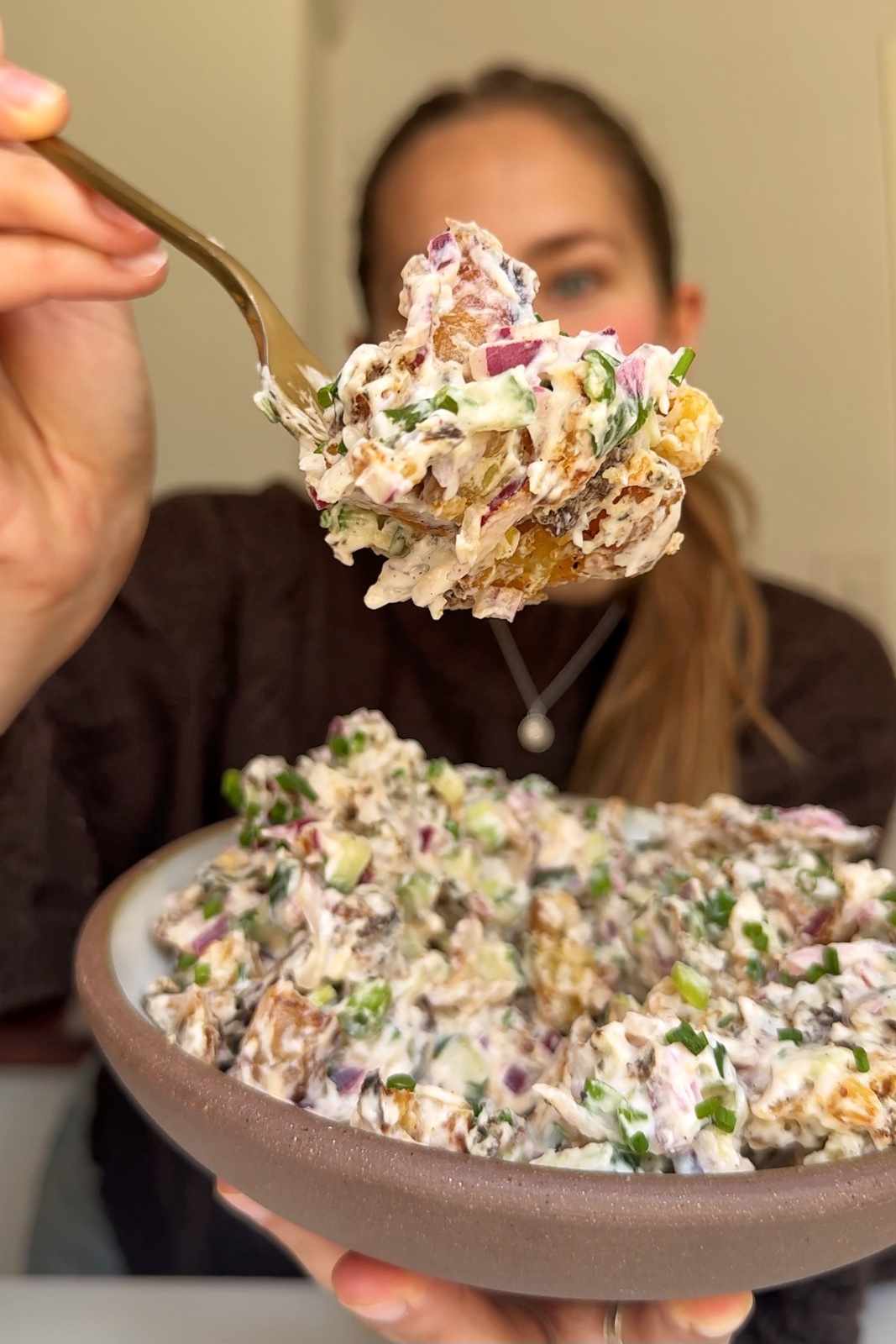 Emily Roz holding crispy potato salad to the camera.