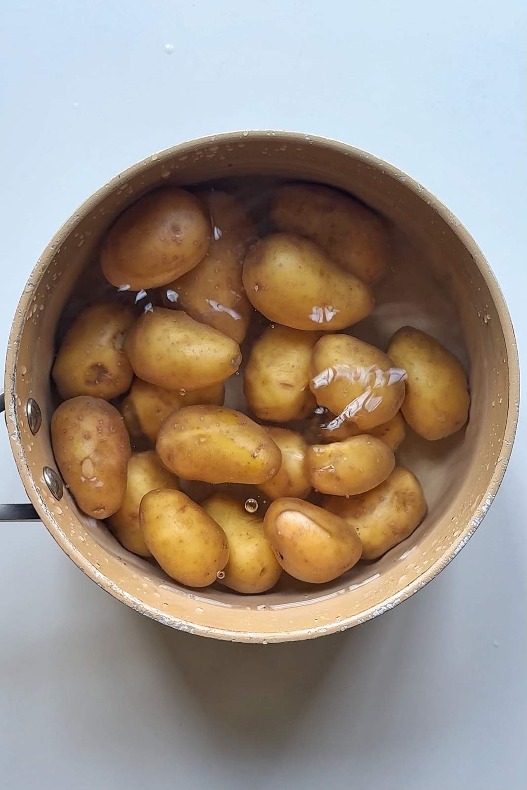 Boiling baby potatoes in a saucepan.
