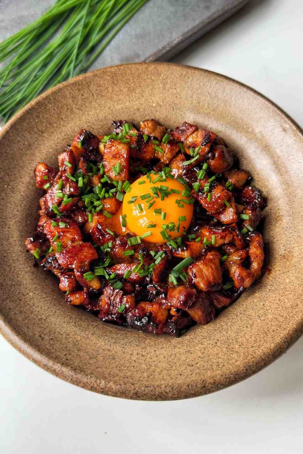 Chopped green chives garnished over a Japanese pork bowl, illustrating how they can be used as a fresh, mild substitute for dill to add color and a bite of flavor.