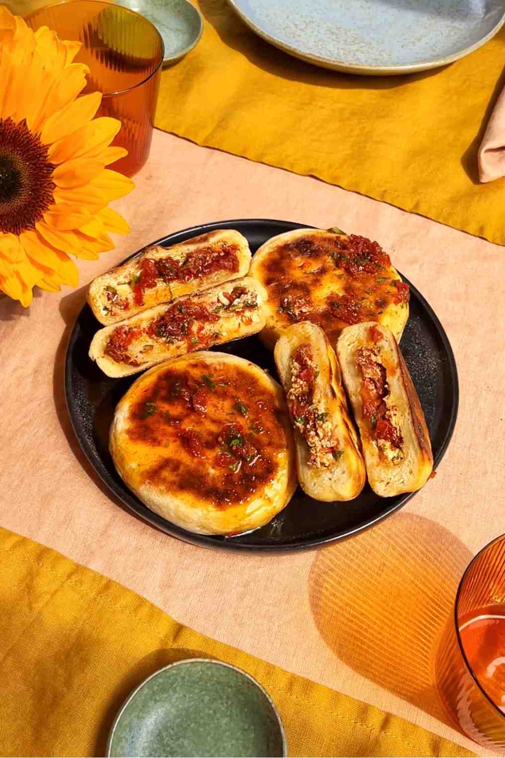 Caprese stuffed flatbreads cut open on a black plate showing sun-dried tomato mozzarella and basil filling.