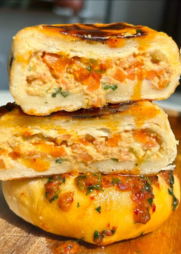Hummus stuffed flatbreads stacked and halved showing the creamy hummus and vegetable filling with a paprika drizzle.