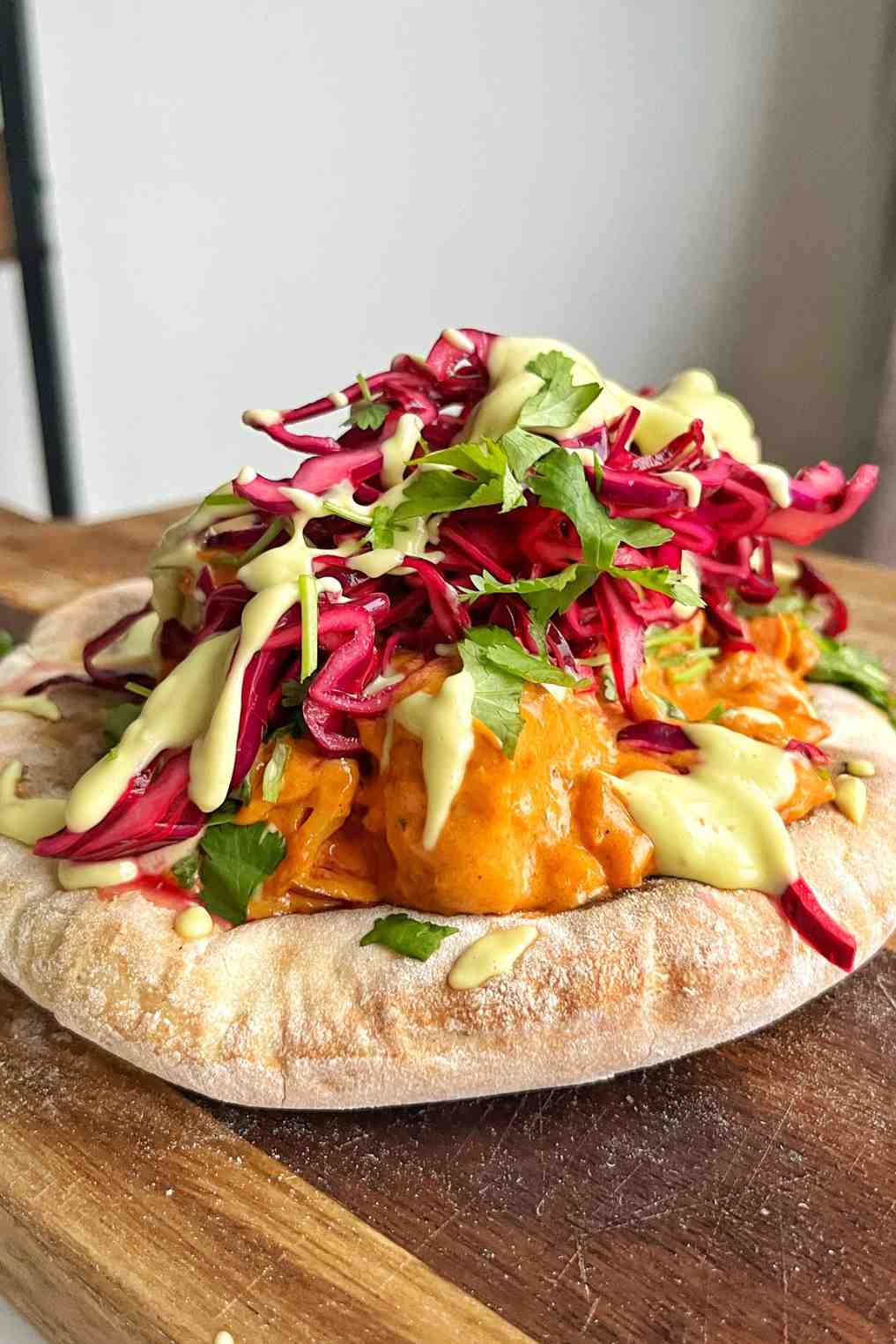 Butter curry naan kebab topped with creamy curry sauce pickled red cabbage avocado drizzle and fresh cilantro.