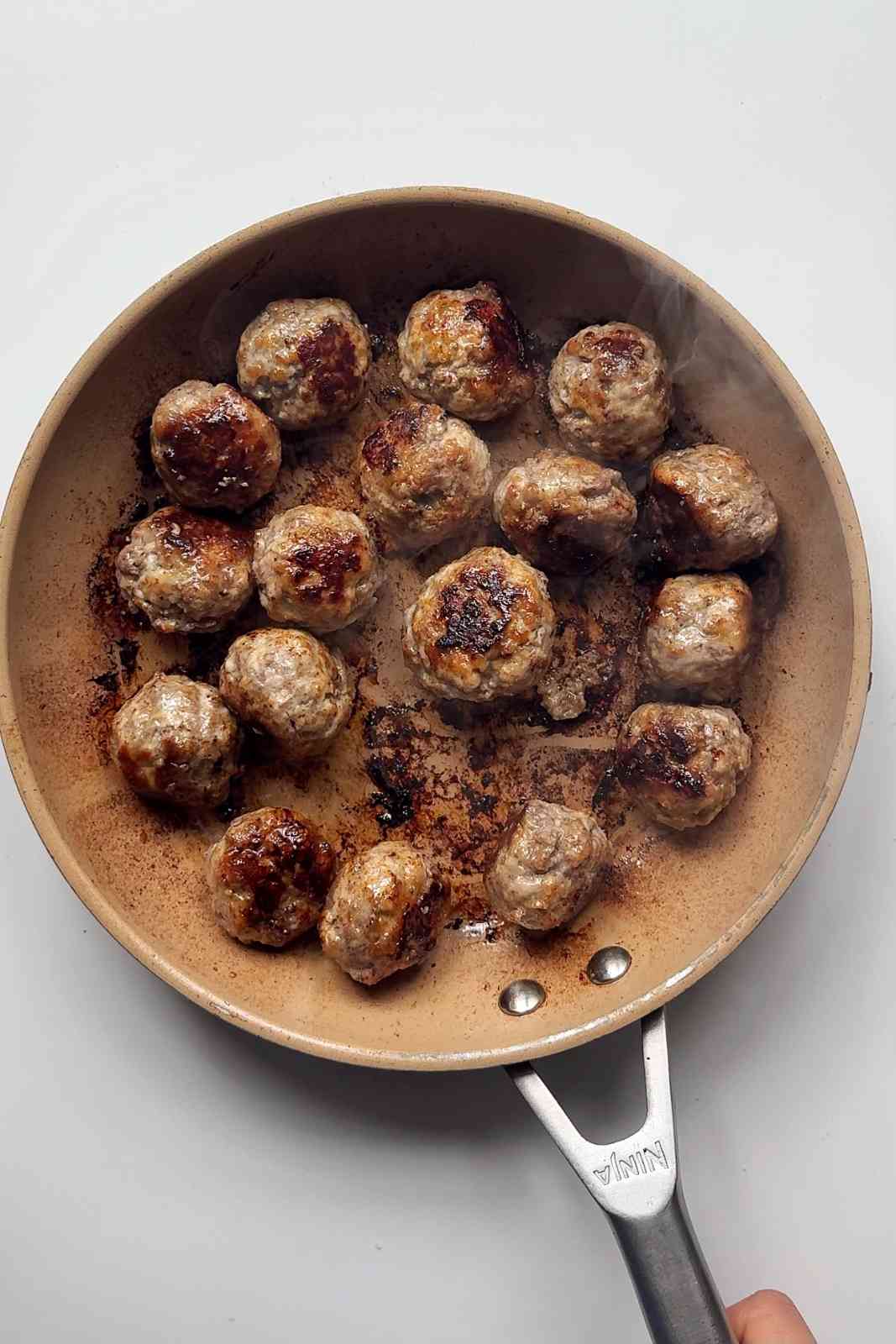 Frying meatballs in skillet.