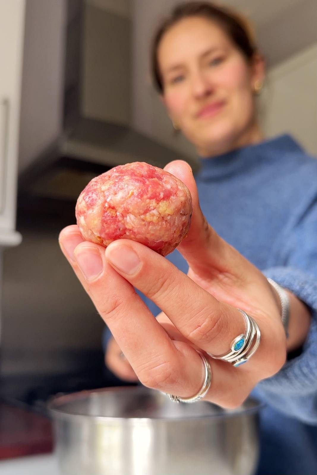 Emily Roz showing an uncooked meatball to the camera.