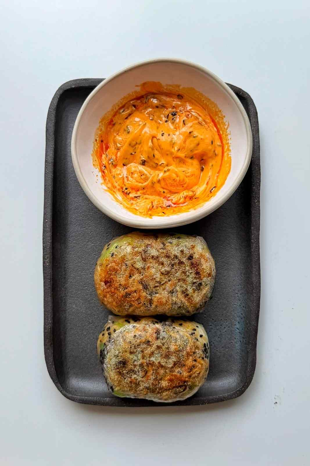 Ramen dumplings with a dipping sauce on a slate plate.