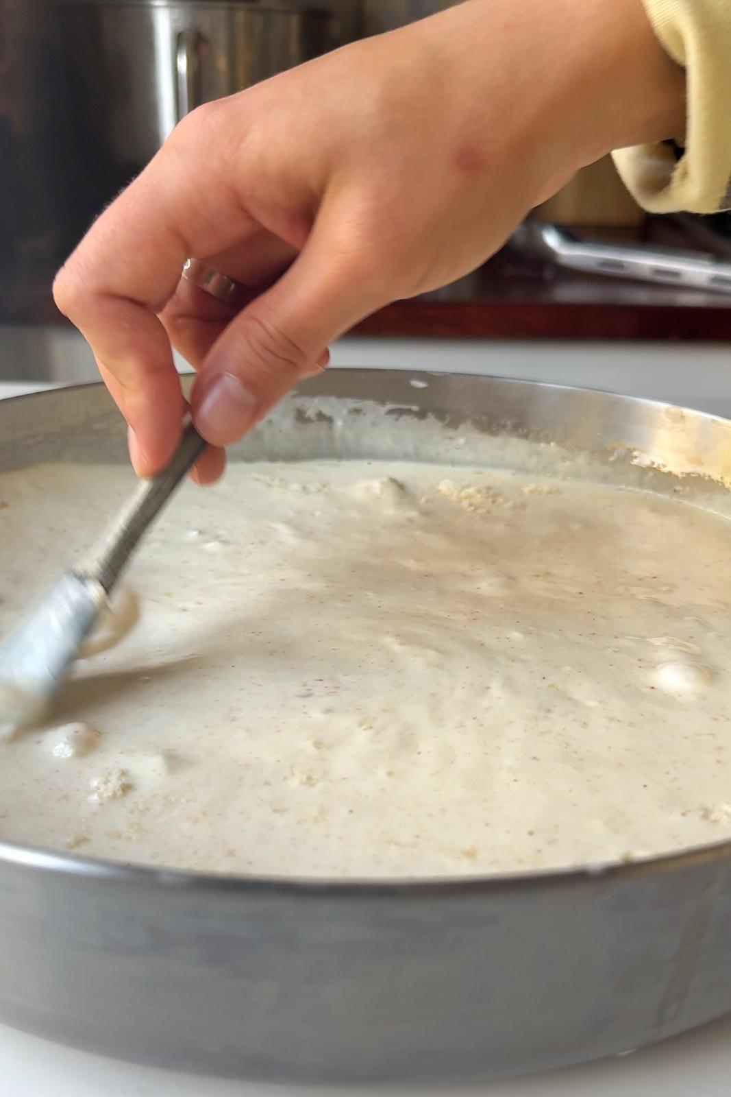 Stirring silken tofu pasta sauce in a stainless steel skillet.