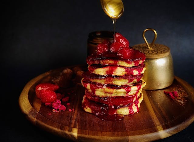 Strawberry fruit syrup poured over pancakes, a creative maple syrup substitute.