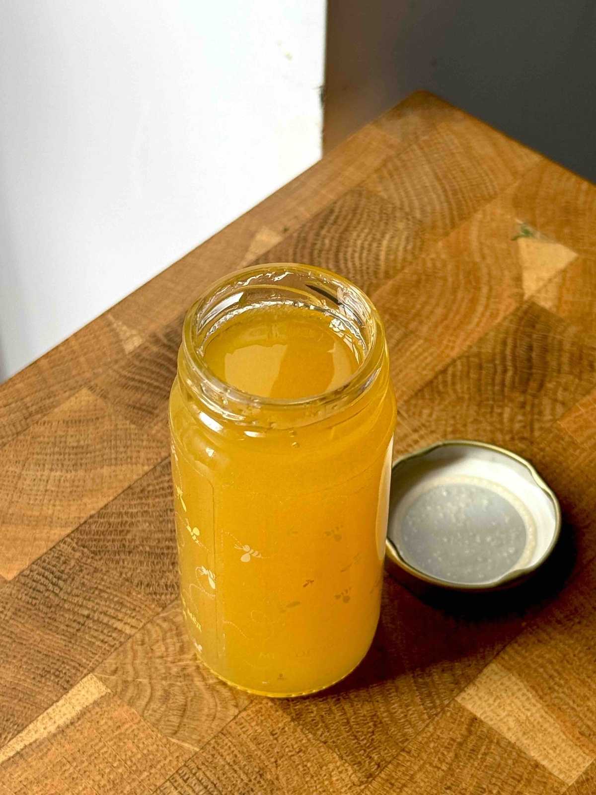 A small jar of honey on a wooden counter top.