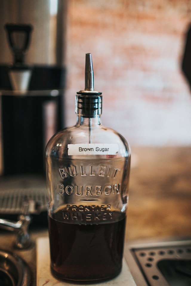 Homemade brown sugar syrup as a substitute for maple syrup, stored in a repurposed glass bottle with a metal pour spout.
