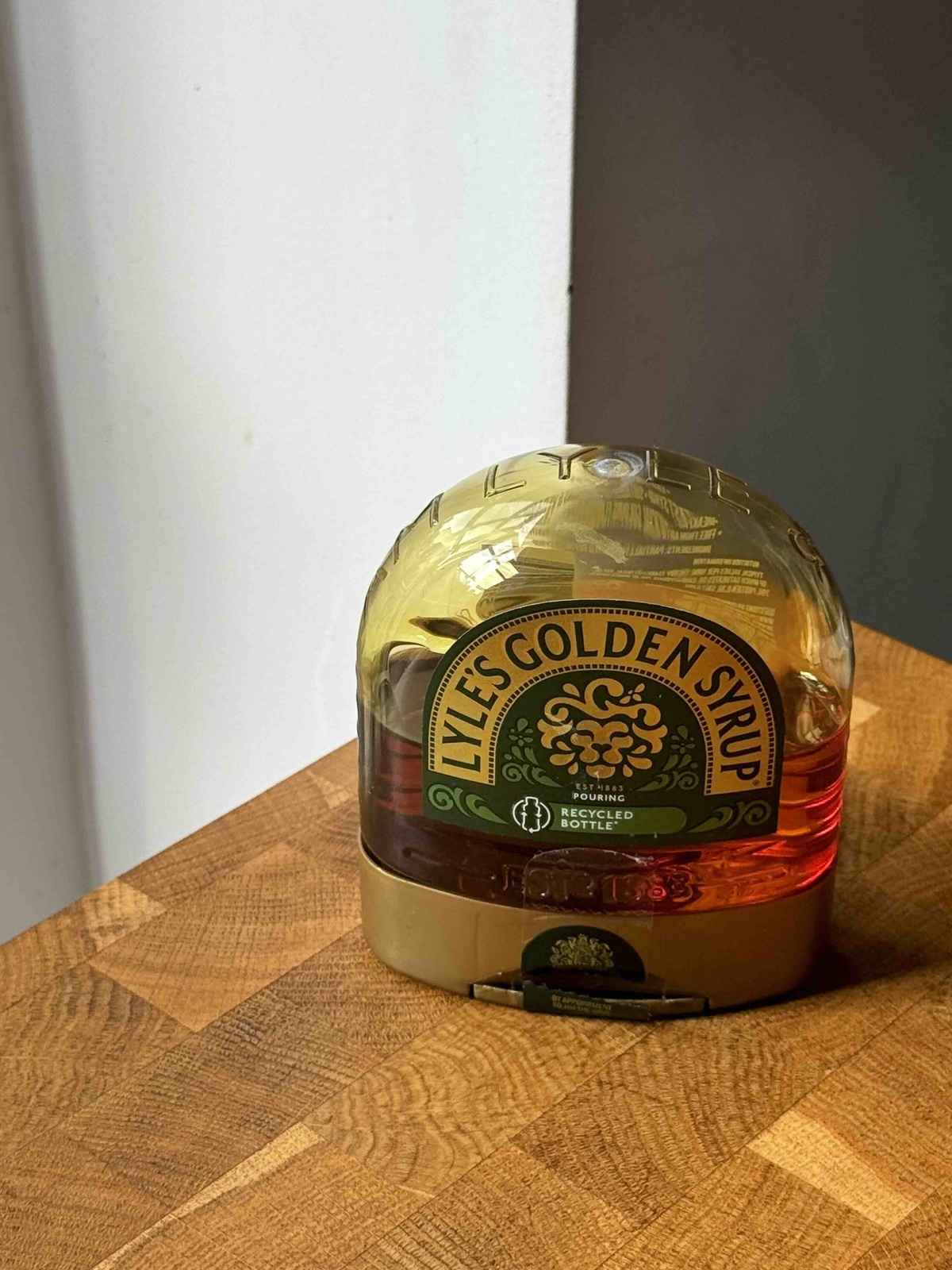 A jar of golden syrup on a wooden counter.