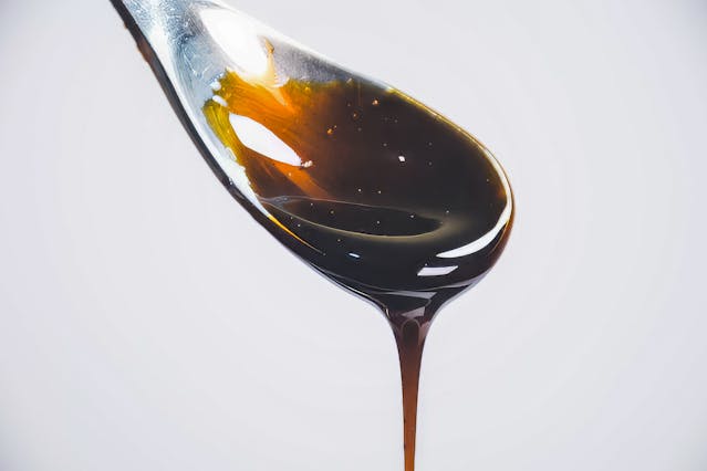 Light molasses dripping from a spoon, a rich maple syrup substitute for baking.