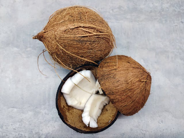 Whole and cracked open coconuts, the source plant for coconut nectar — a natural maple syrup substitute.