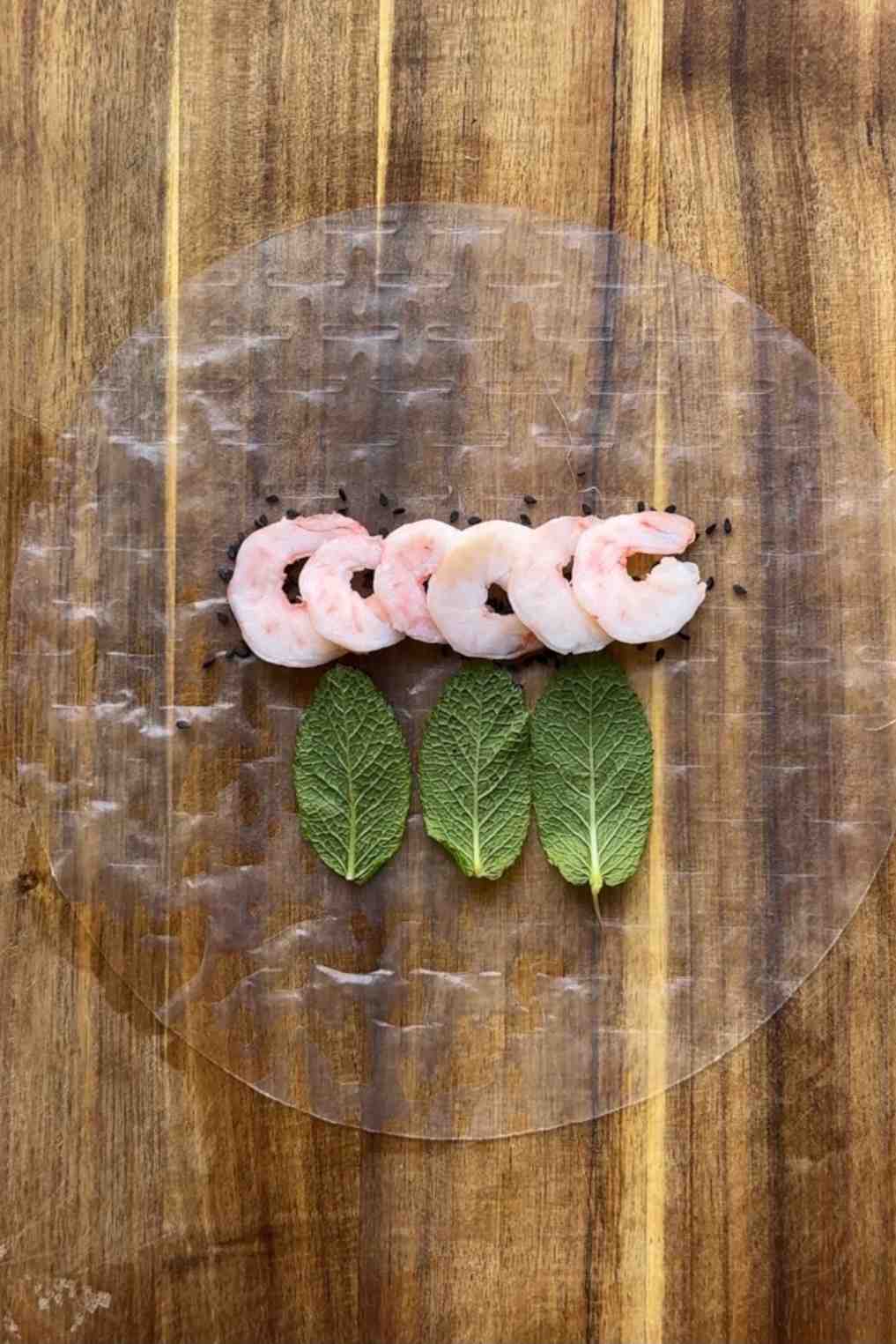 Laying prawns and mint down onto a piece of rice paper.