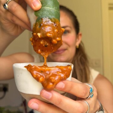 Emily Roz dipping a summer roll in peanut dipping sauce.