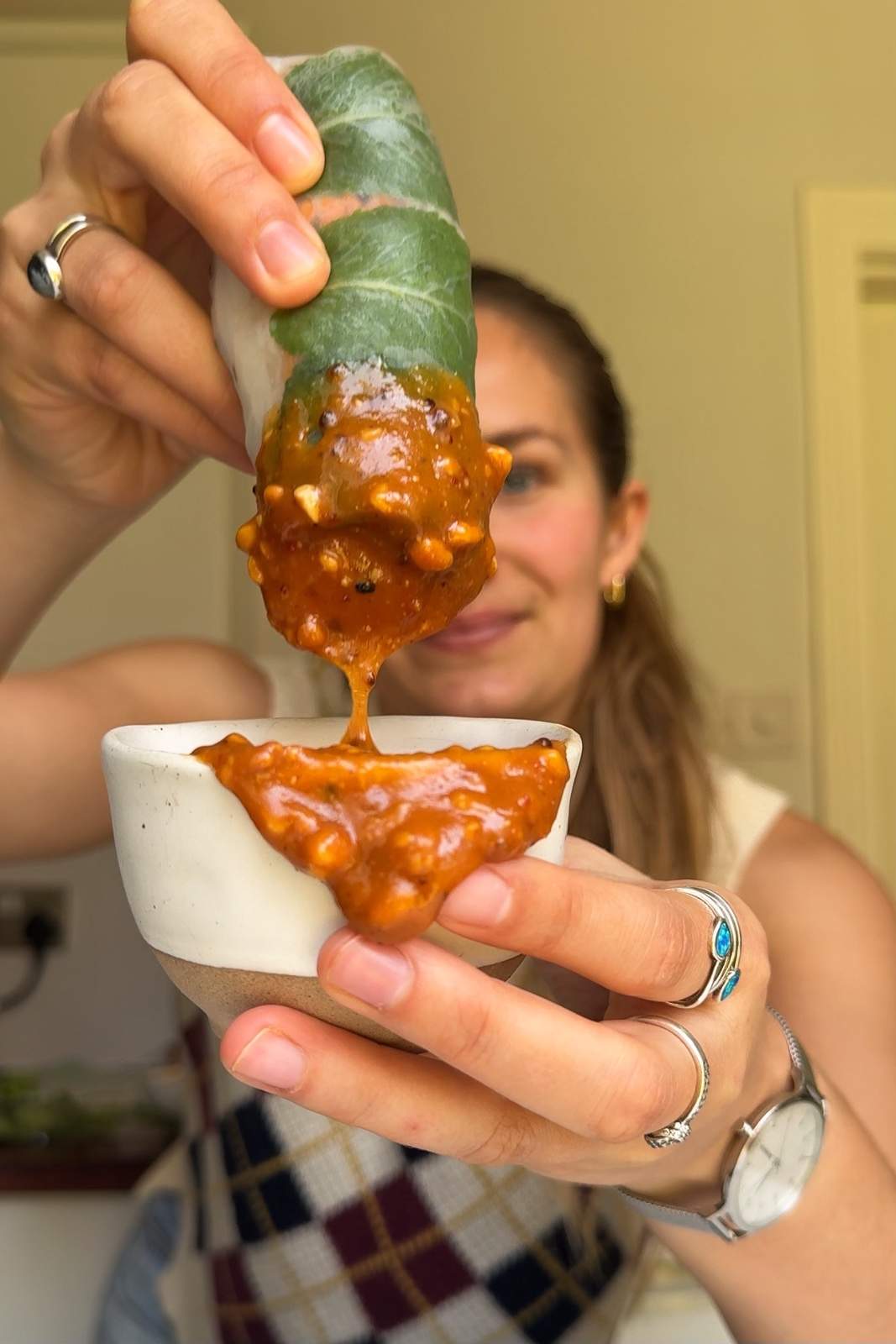 Emily Roz dipping a summer roll in peanut dipping sauce.
