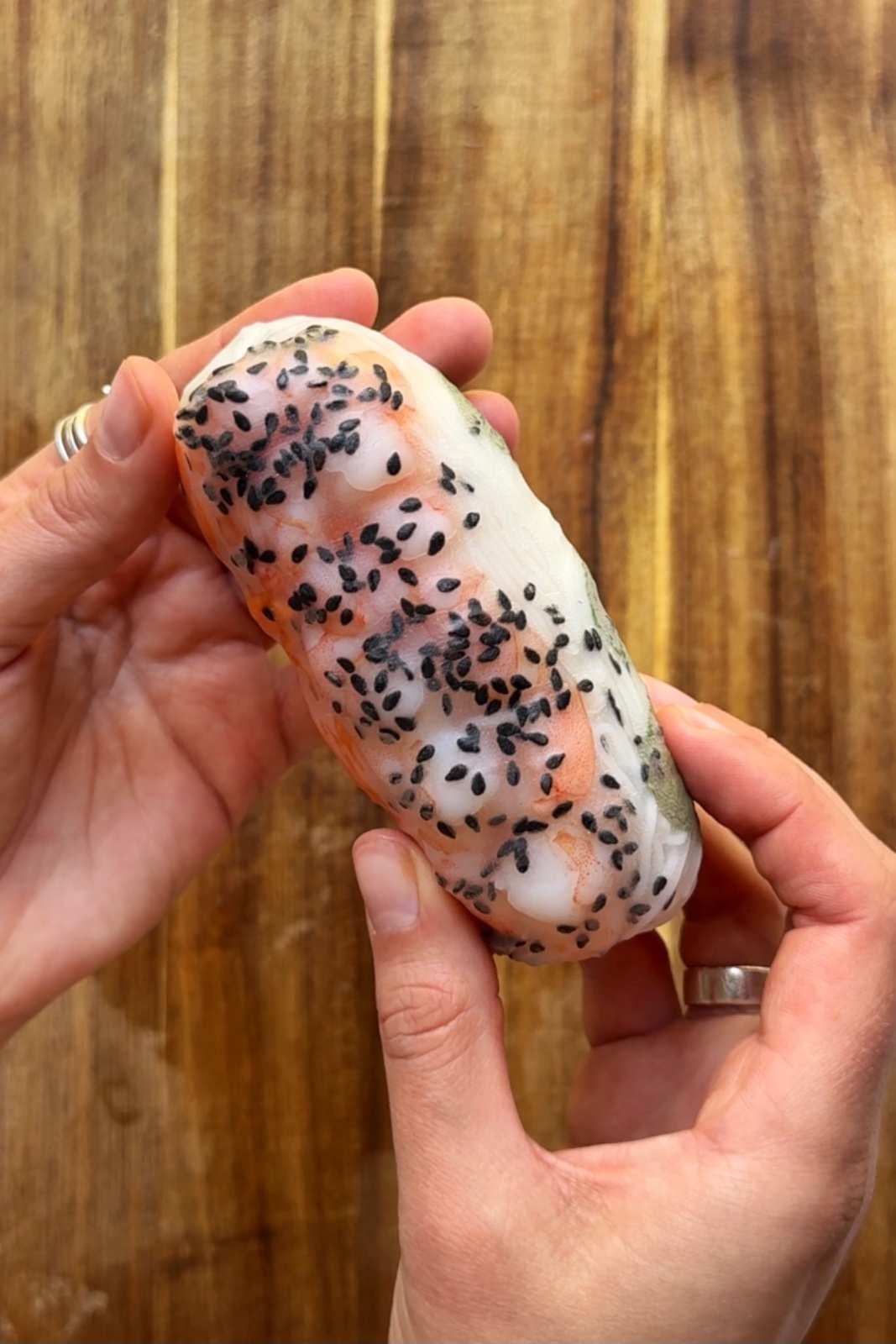 Shrimp summer roll held in hands.