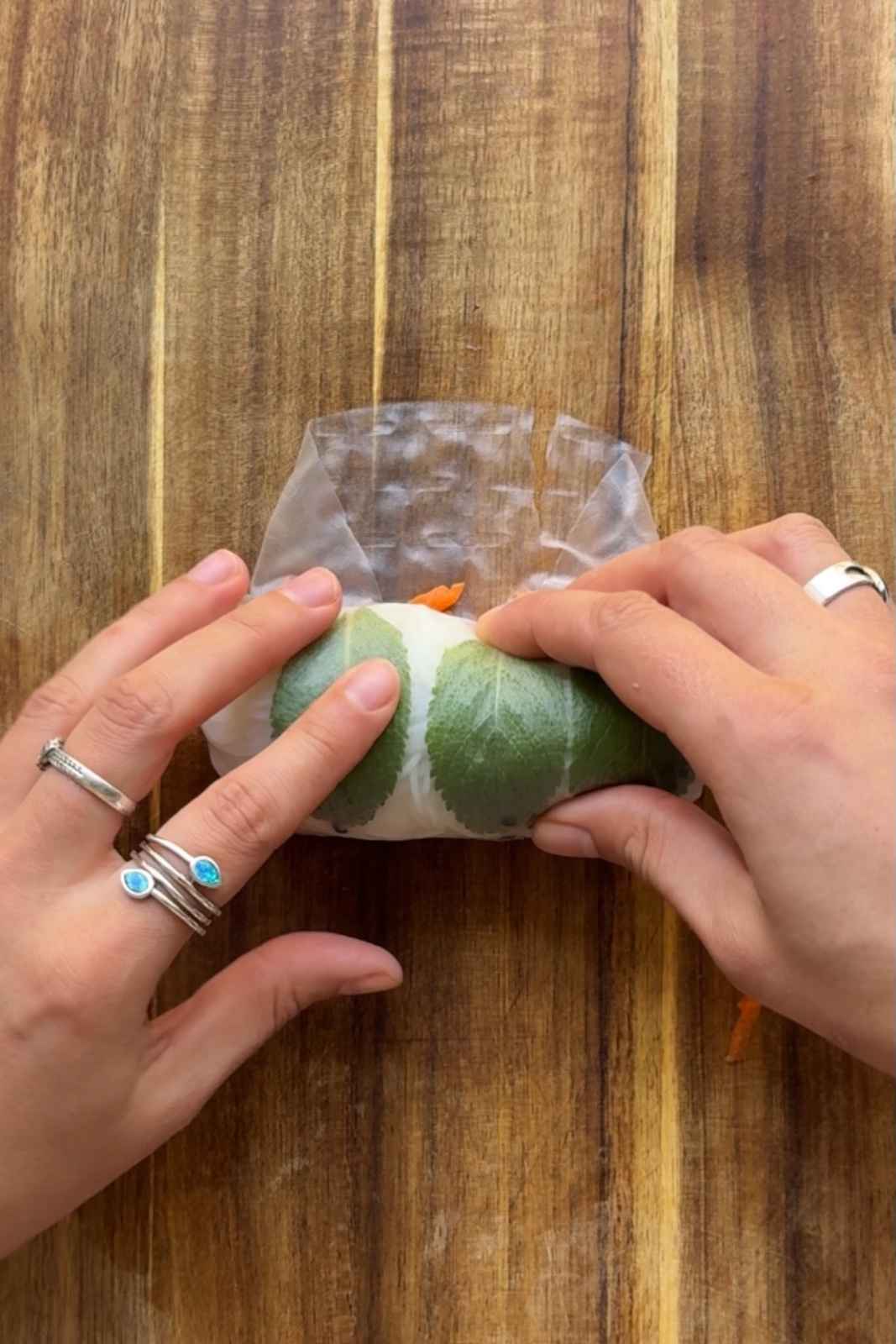 Rolling summer rolls on a wooden chopping board.