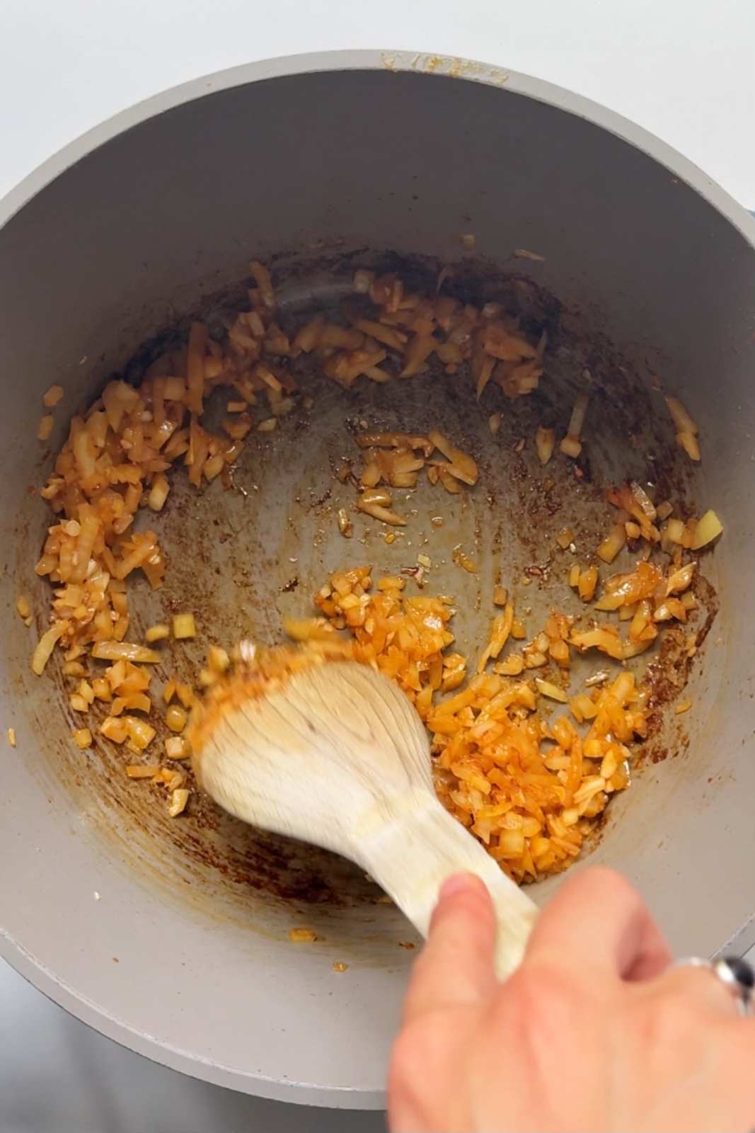 Frying garlic, ginger, and onion in pot.