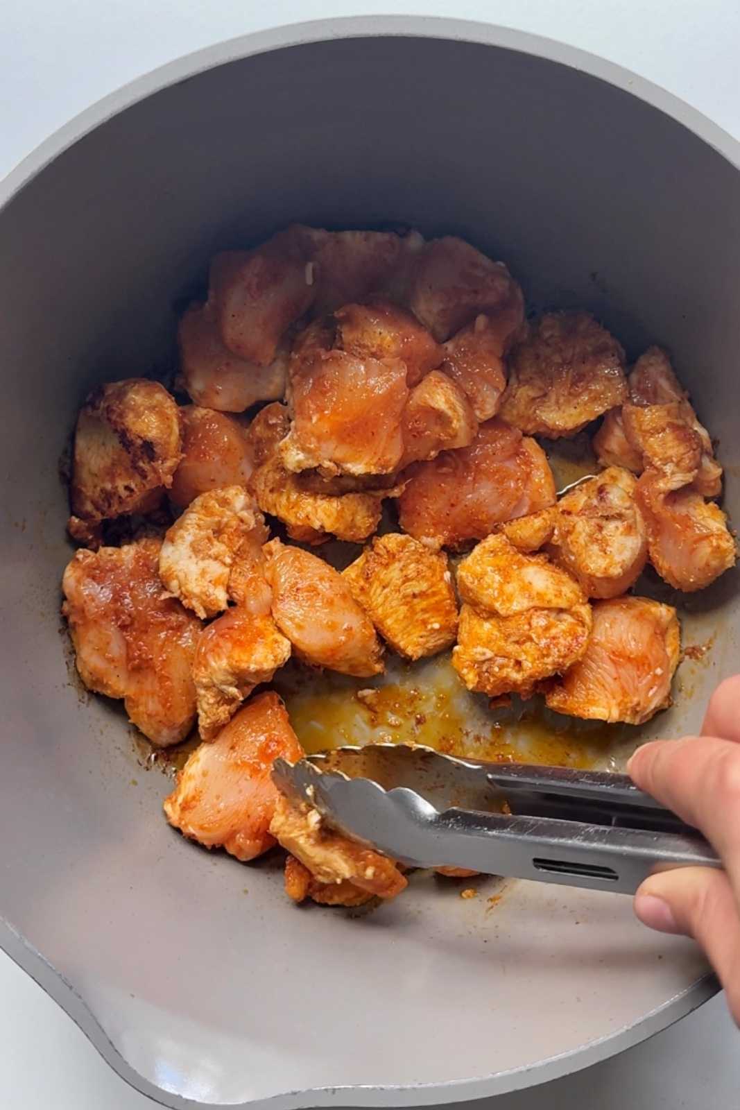 Frying chicken in a pot for thai peanut coconut chicken curry.