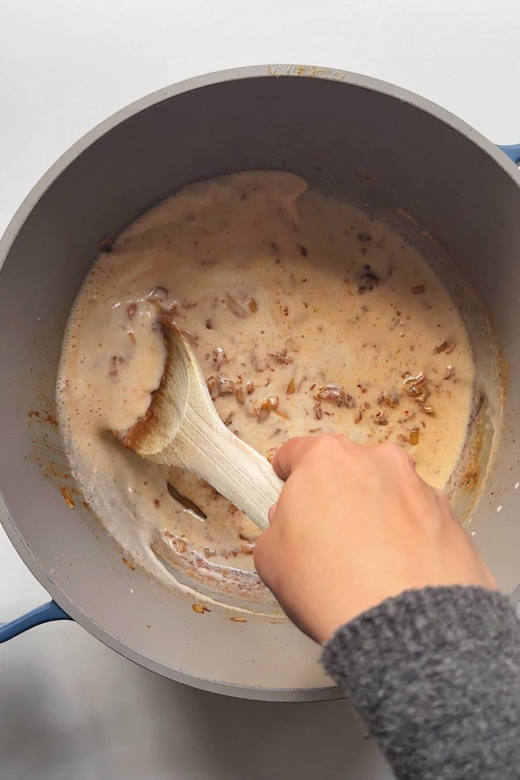 Stirring the peanut coconut sauce in a pot.