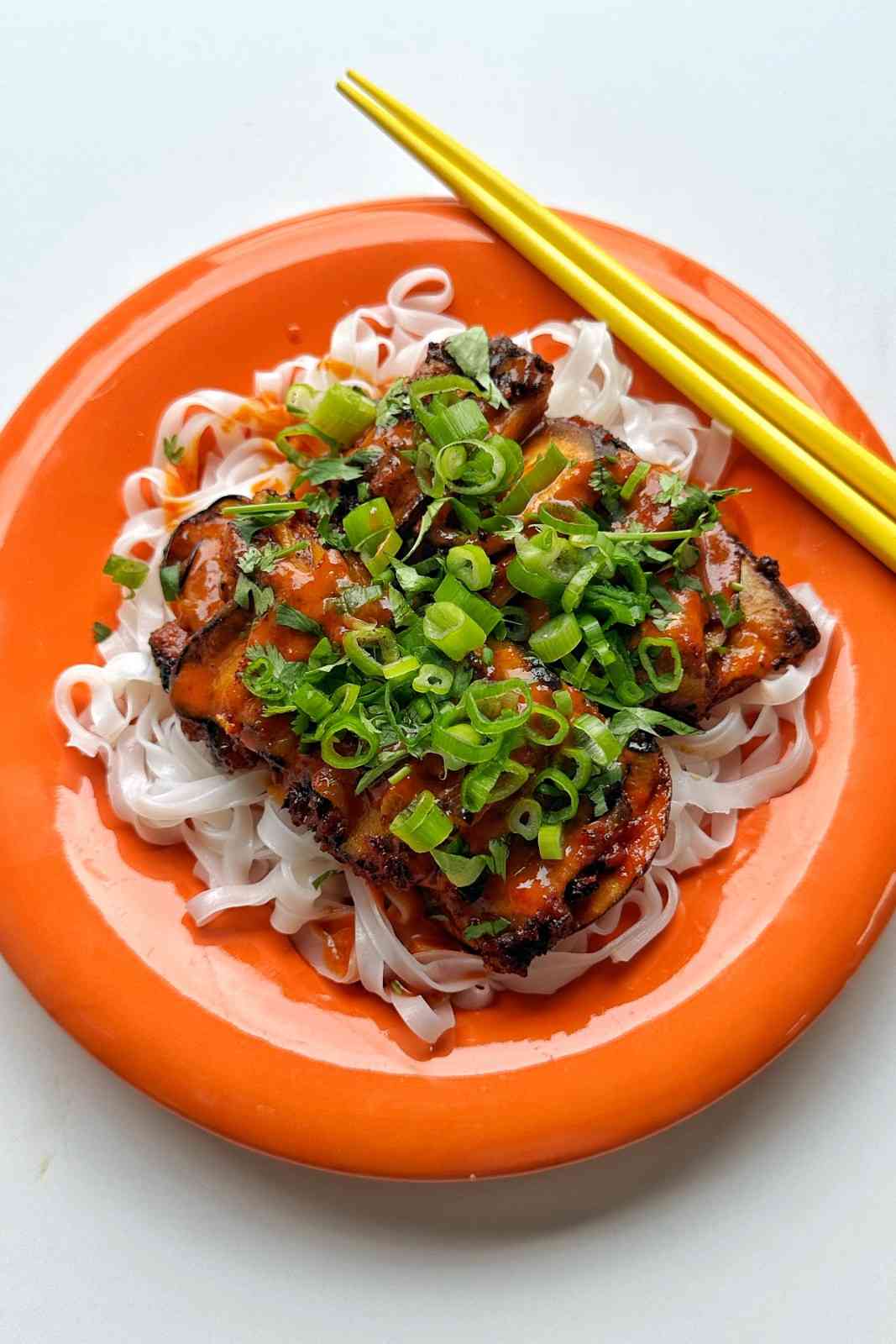 Gochujang eggplant skewers brushed with glossy red gochujang peanut sauce served on rice noodles with cilantro and scallions.