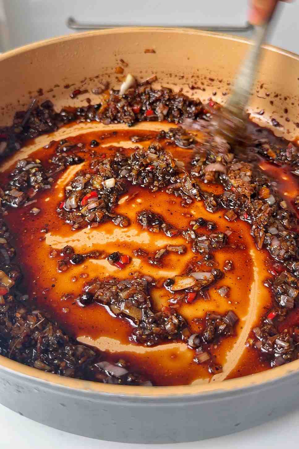 Stirring black pepper tofu sauce in pan.