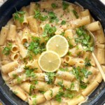 Creamy lemon Boursin pasta with rigatoni in a black pan, topped with parsley, chili flakes, Parmesan and lemon slices.