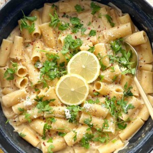 Creamy lemon Boursin pasta with rigatoni in a black pan, topped with parsley, chili flakes, Parmesan and lemon slices.