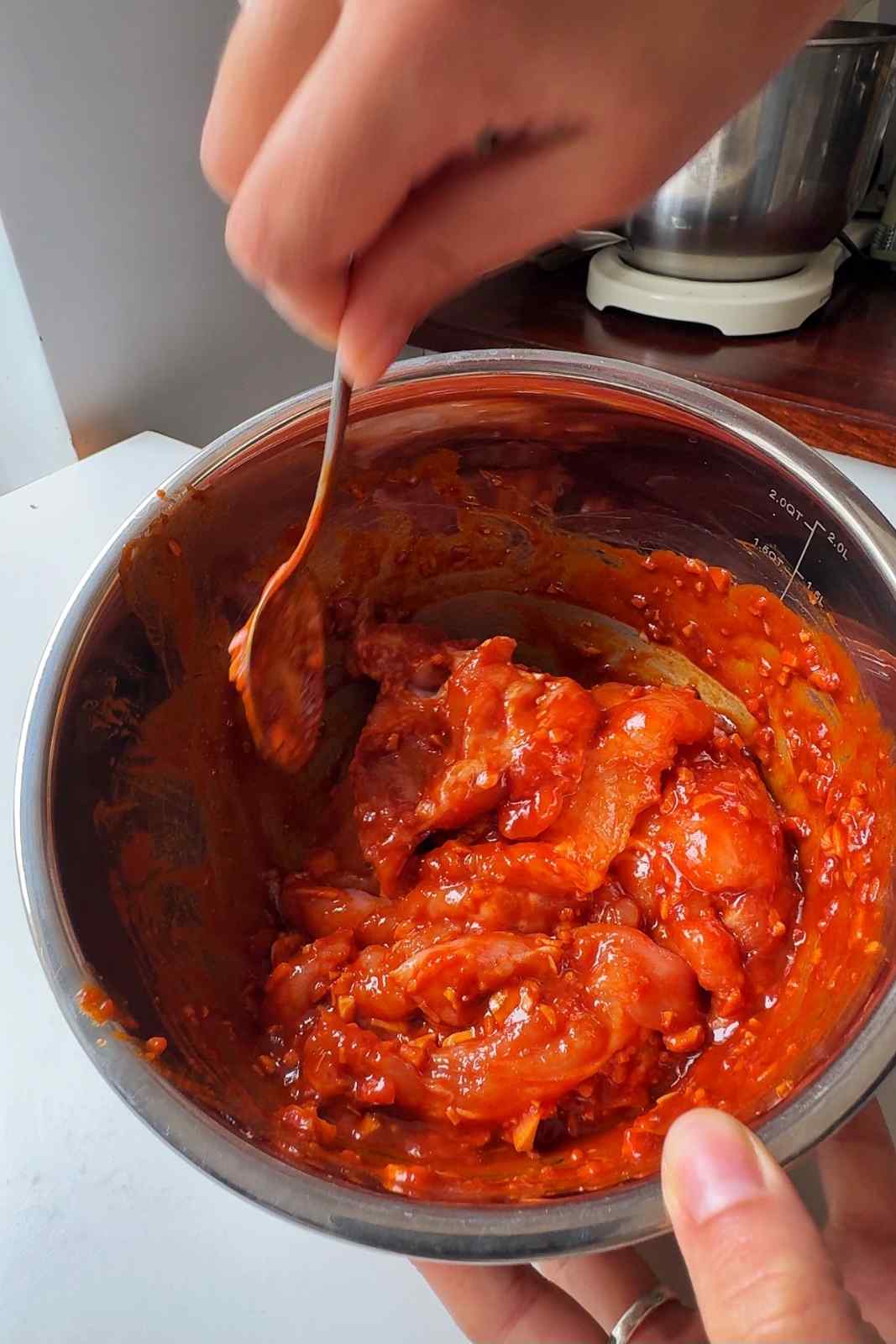 Marinating chicken in a stainless steel bowl.