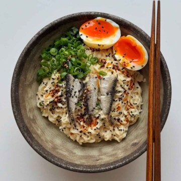 sardine ramen with jammy egg, scallions, and chopsticks.
