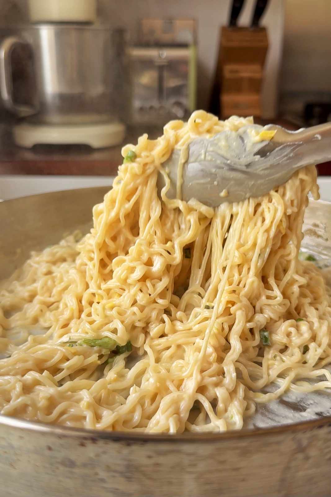 Using metal tongs to serve sardine noodles.