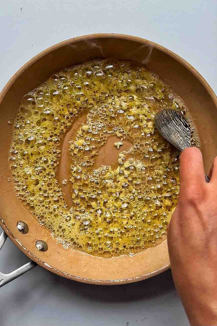 Frying garlic in a pan with butter and oil.