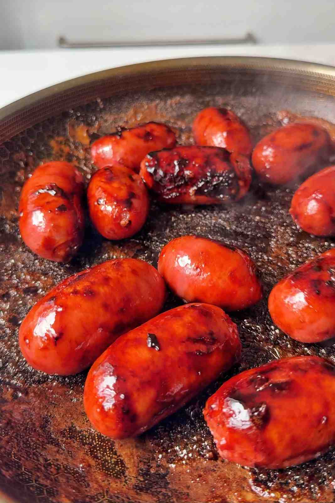 Cooking the longganisa in a pan.