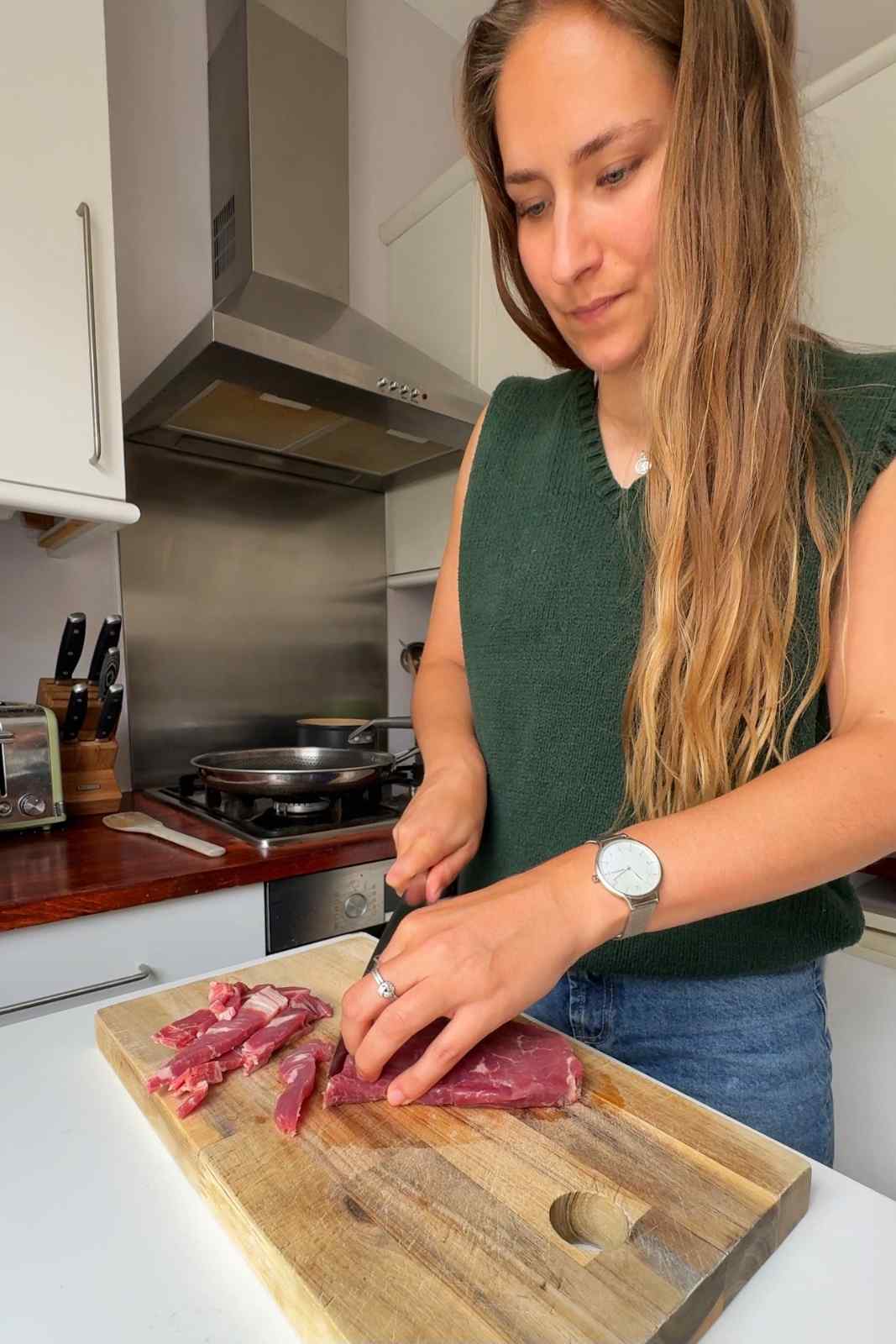Slicing steak on wooden chopping board.
