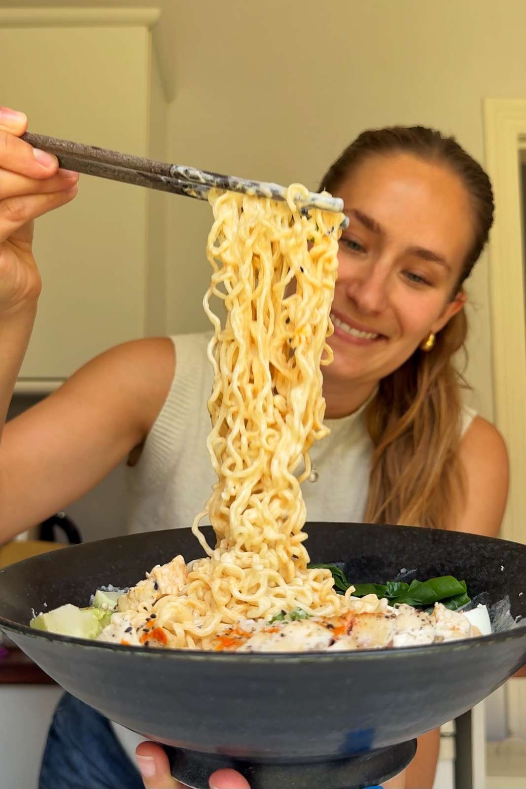 Emily Roz lifting up chicken caesar ramen with chopsticks.