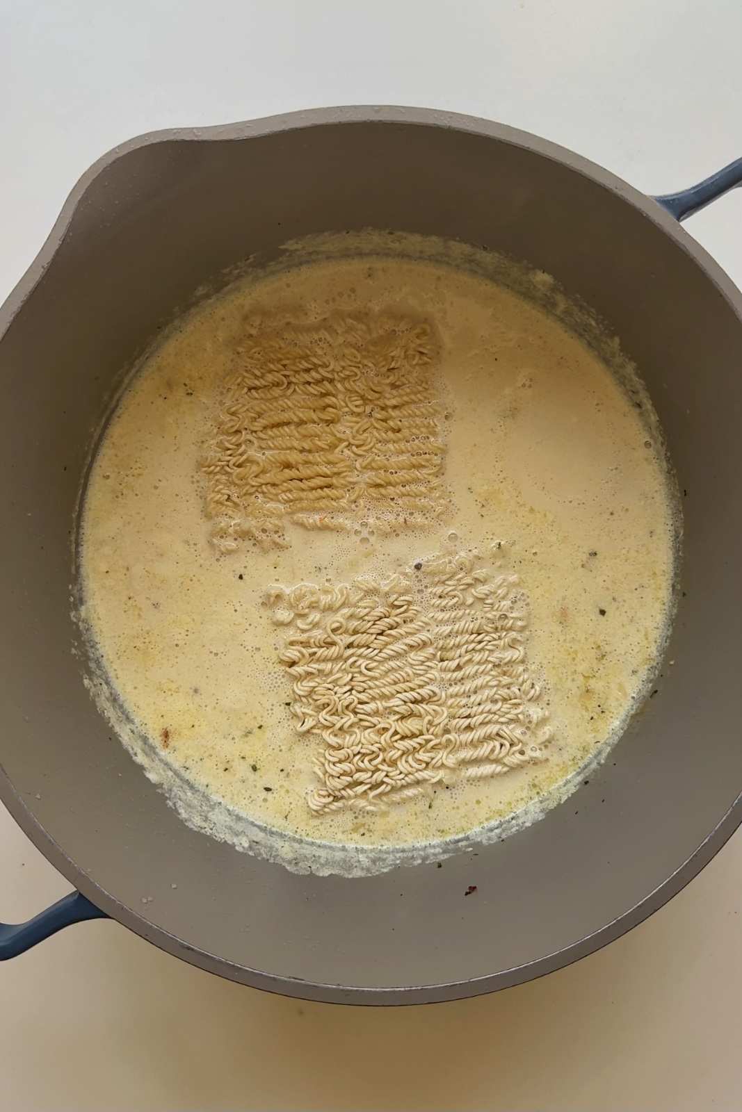 Noodles cooking in chicken caesar ramen sauce.