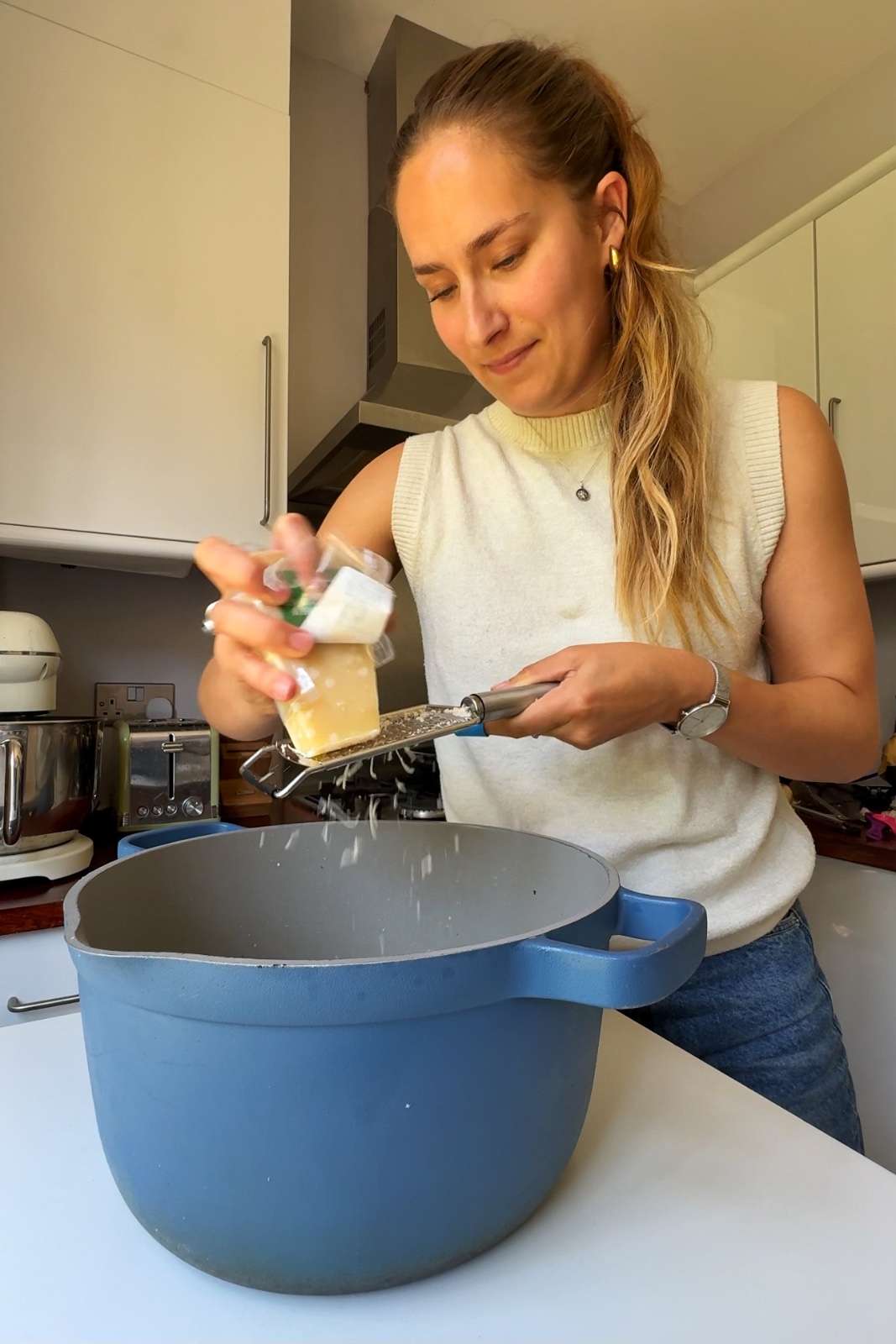 Grating parmesan into a large blue pot.
