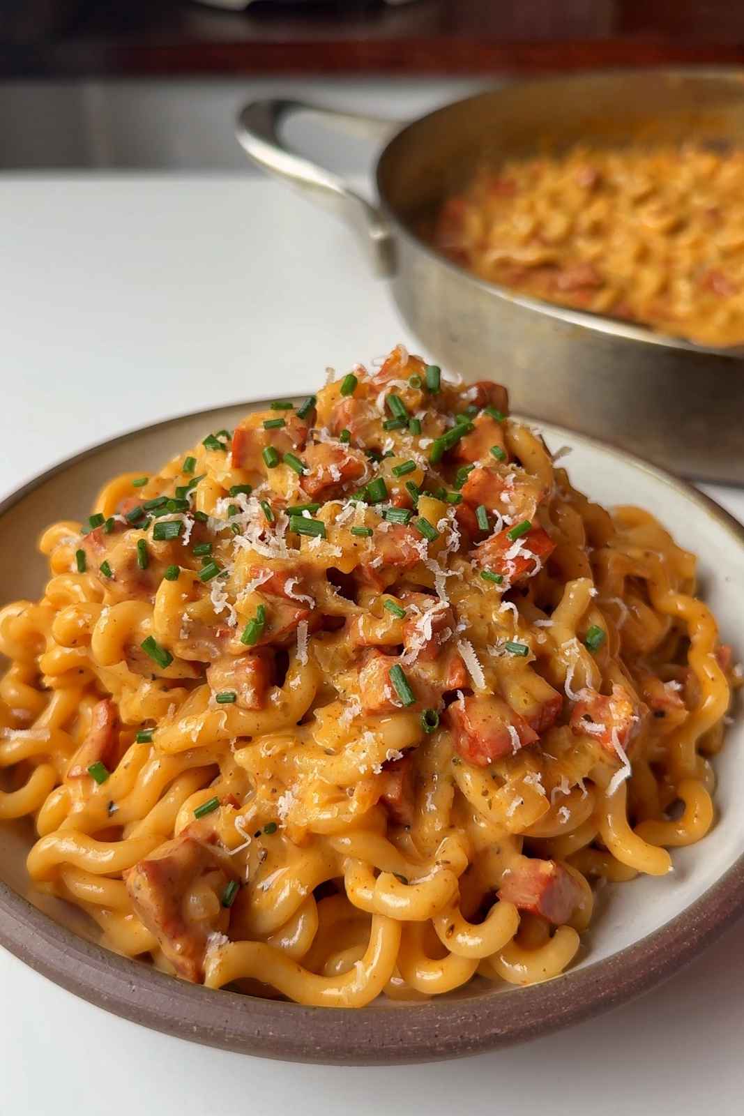 a bowl of creamy chorizo pasta topped with parmesan and chives