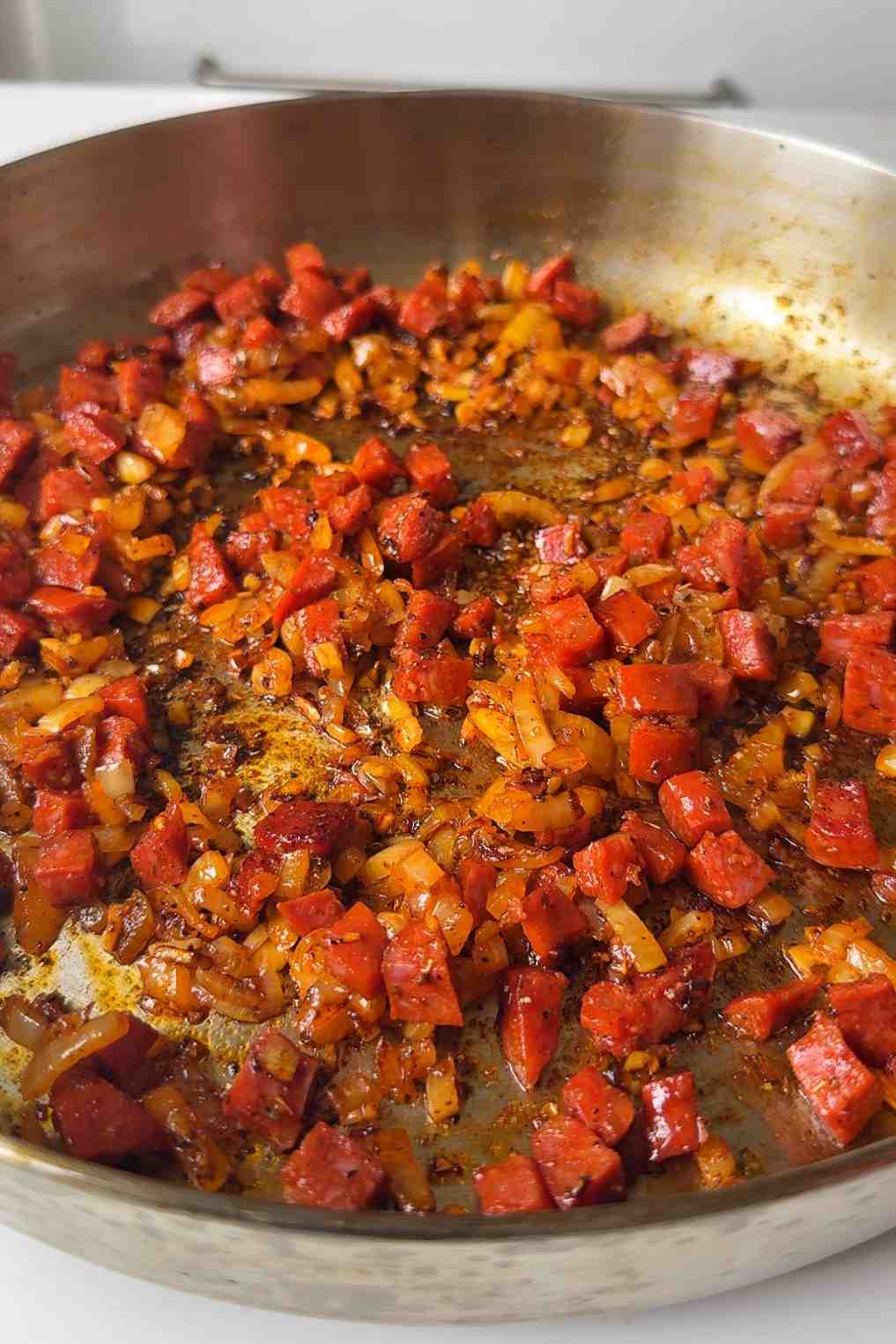 Frying chorizo in a pan with onions and garlic.