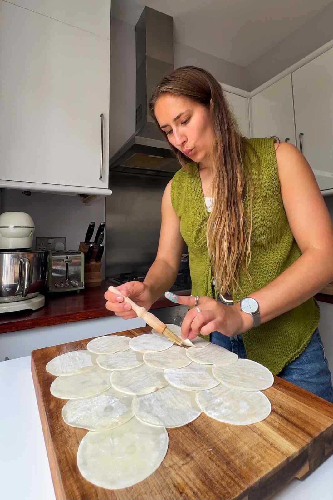 Emily brushing the underside of the dumpling wrappers with water.
