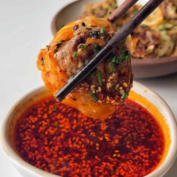 Dumpling wheel being dipped in chilli oil broth.
