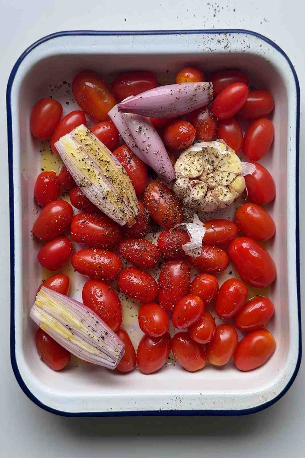 Baby tomatoes in a tin with shallots and garlic.