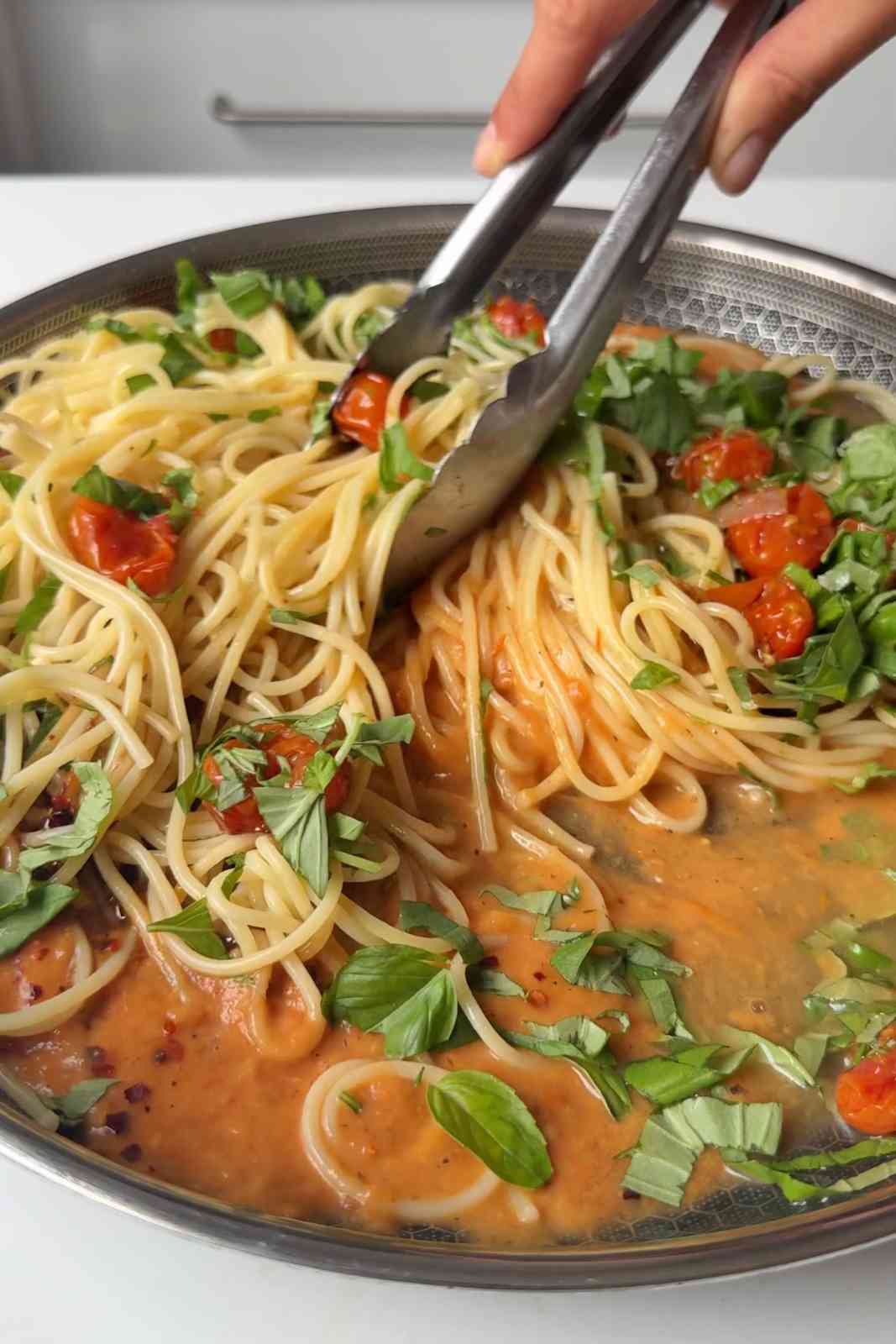 Stirring roasted tomato pasta sauce with spaghetti.
